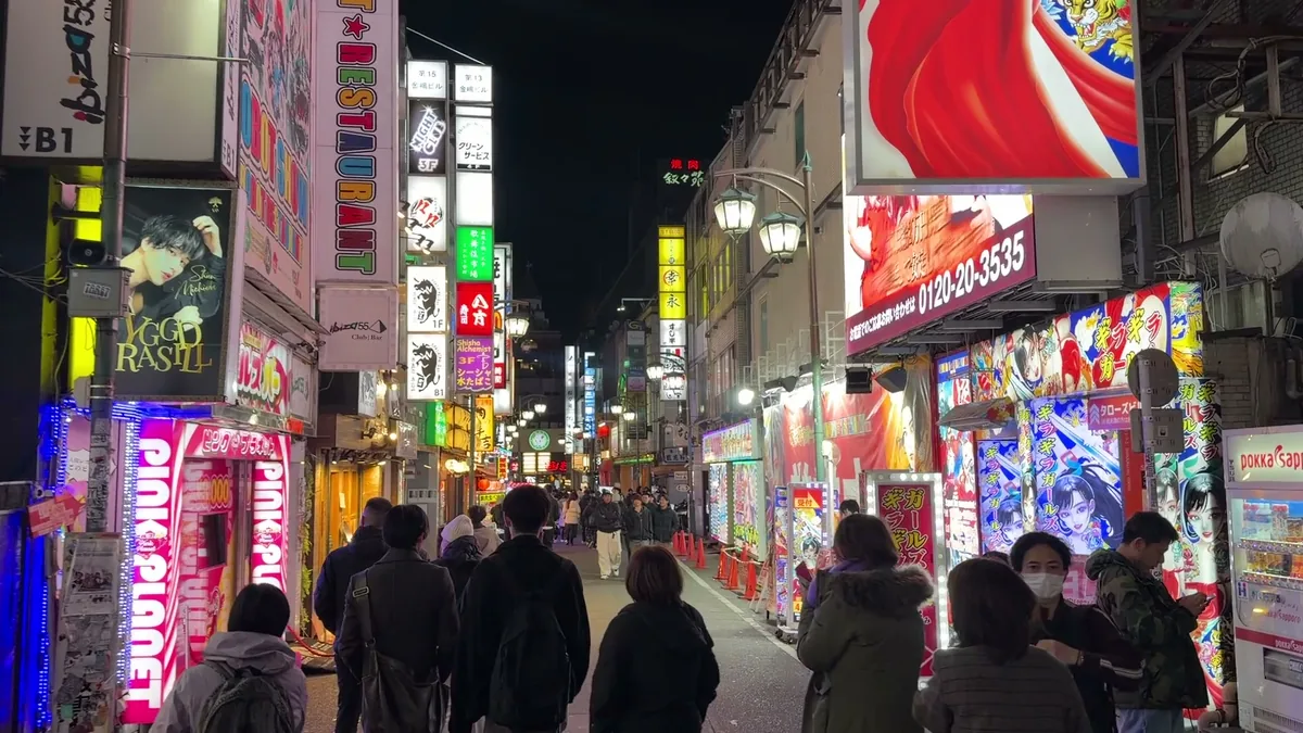 A crowded Kabukicho side street at night lined with host-club and bar signs